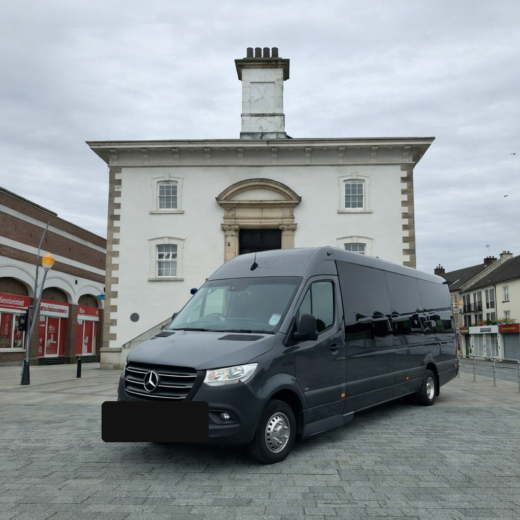 Ace Cabs dark grey Mercedes 22-seater coach parked in a Northern Ireland town square for large group transport