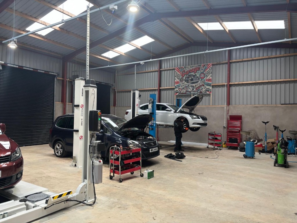 Mechanics servicing Ace Cabs fleet vehicles on hydraulic lifts in the Antrim service centre