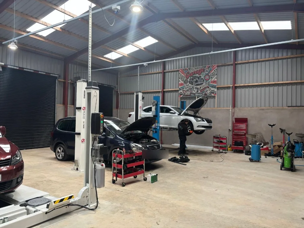 Mechanics servicing Ace Cabs fleet vehicles on hydraulic lifts in the Antrim service centre