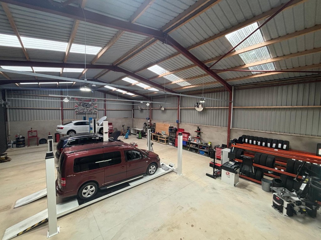 Wide view of the Ace Cabs in-house service centre with vehicle lifts, tyre equipment, and fleet maintenance bays in Antrim