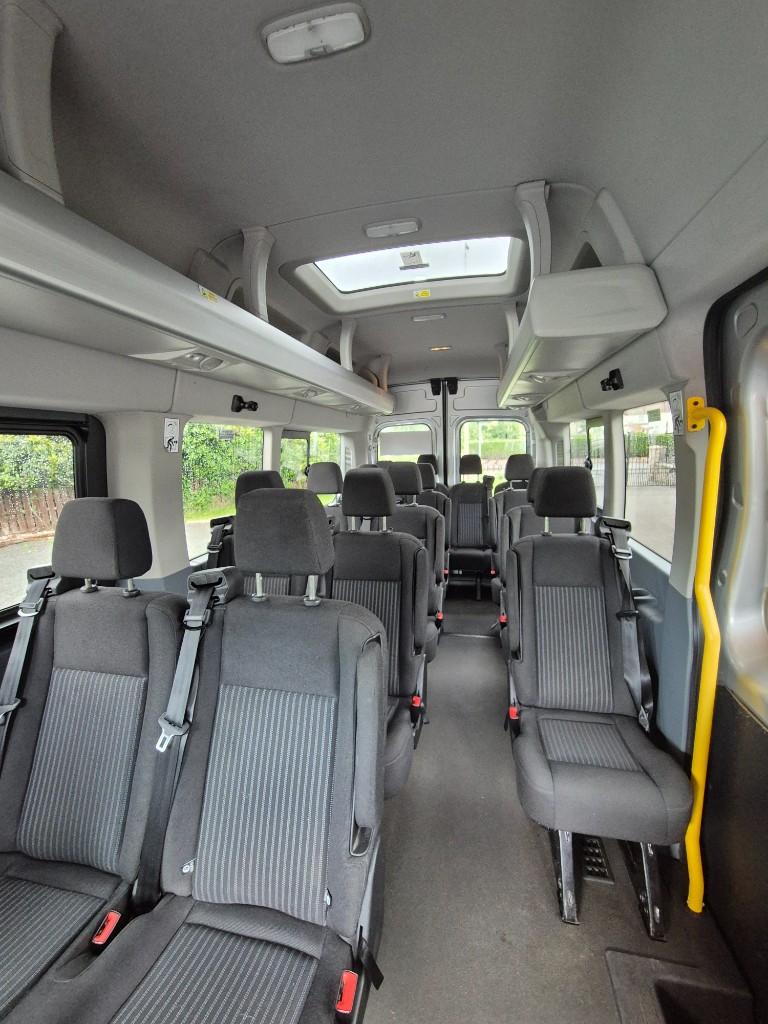 Interior of Ace Cabs Ford Transit minibus with seatbelts and passenger seating for group travel in Northern Ireland