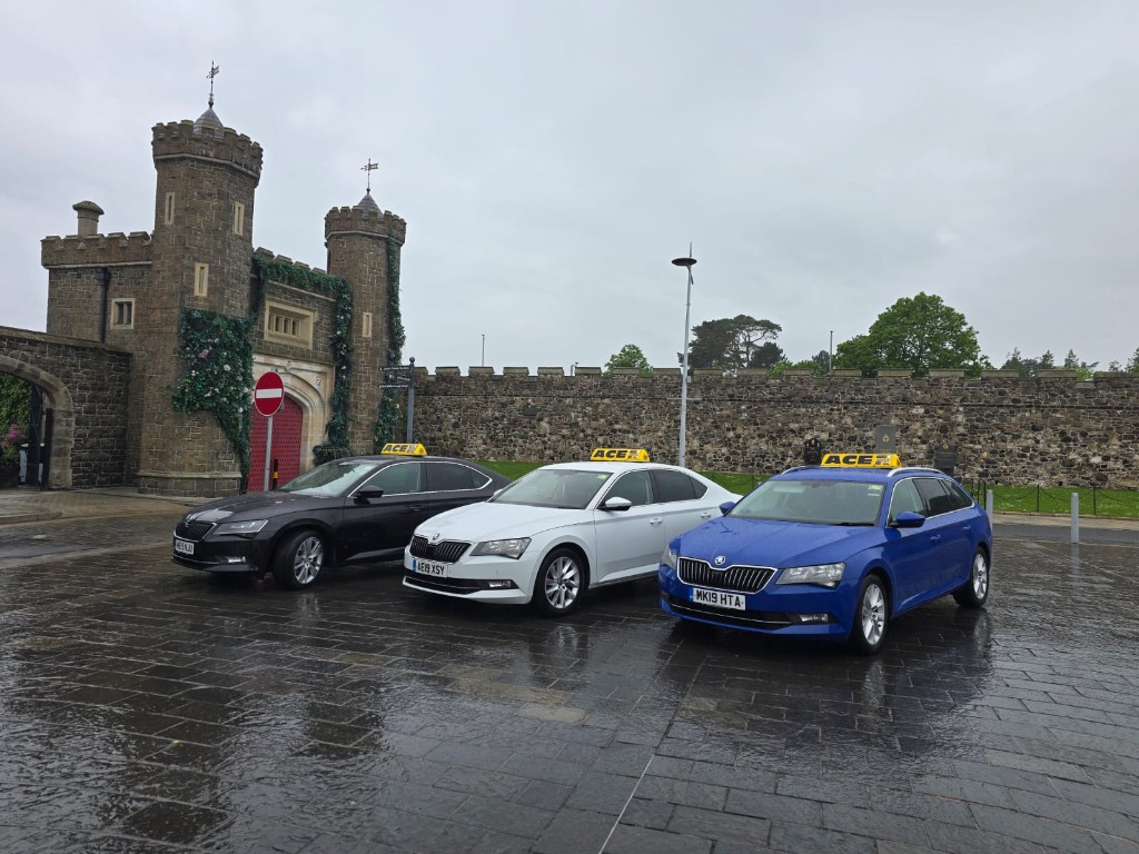 Ace Cabs private hire taxis with ACE roof signs: black, white, and blue saloons at Antrim gatehouse, Northern Ireland