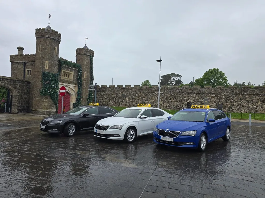 Ace Cabs private hire taxis with ACE roof signs: black, white, and blue saloons at Antrim gatehouse, Northern Ireland