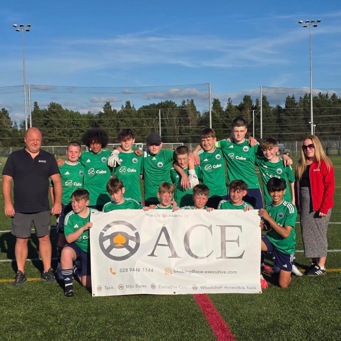Antrim Soccer Academy 2012 squad with Ace Cabs sponsorship banner on the pitch