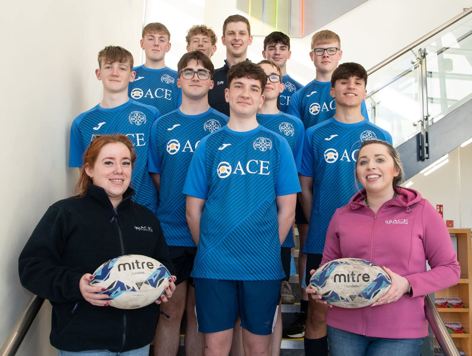 Parkhall Integrated College U16 rugby team in Ace Cabs sponsored blue kits on school staircase