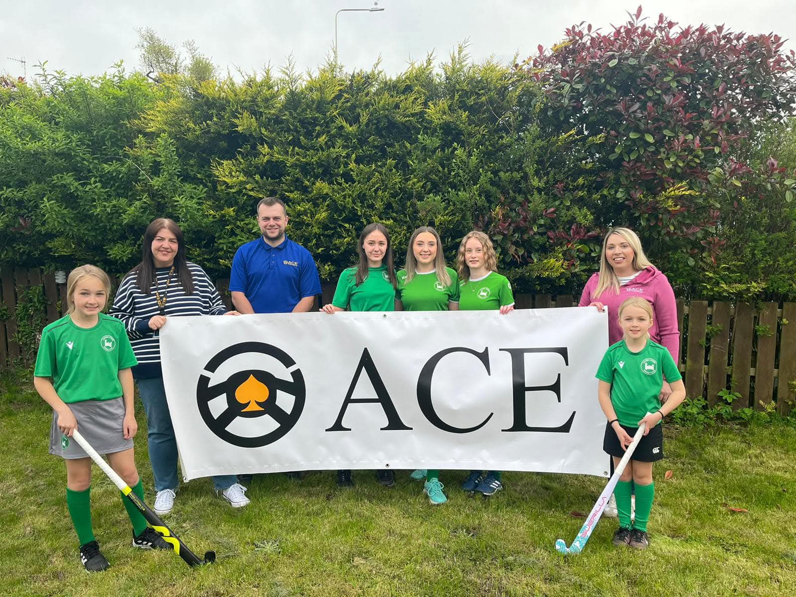 Randalstown Ladies Hockey Club youth players with Ace Cabs sponsorship banner