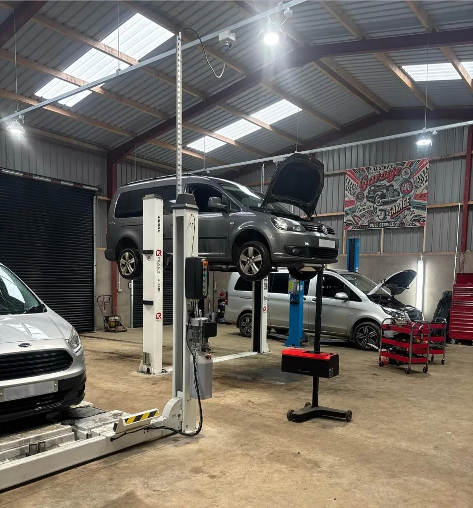 Ford Transit and Volkswagen fleet vehicles undergoing routine maintenance at Ace Cabs garage